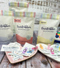 EverEmblem pre-cut cotton and satin labels in colorful packaging. Variety of labels displayed with sewing clips. Ideal for branding handmade crafts and goods