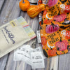 EverEmblem satin Halloween labels with ghost design, displayed with a festive ‘Trick or Treat’ fabric bag and seasonal gourds, perfect for custom handmade projects